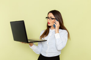front-view-of-female-office-worker-in-white-shirt-and-black-skirt-holding-and-using-laptop-on-green-desk-office-business-busy-work-job-woman